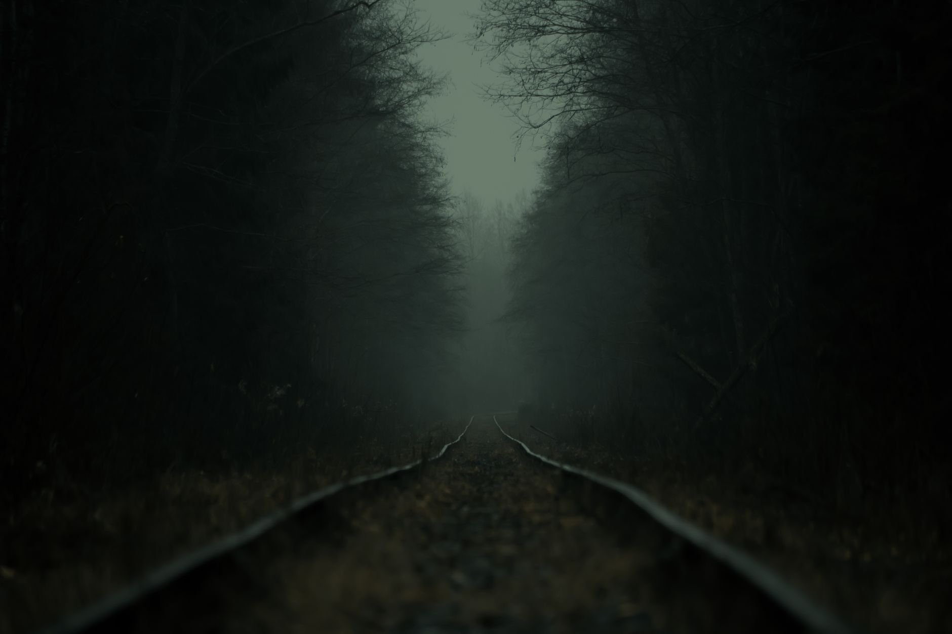A dark atmospheric railroad running through a foggy forest — evocative of Veilcraft's first game world.