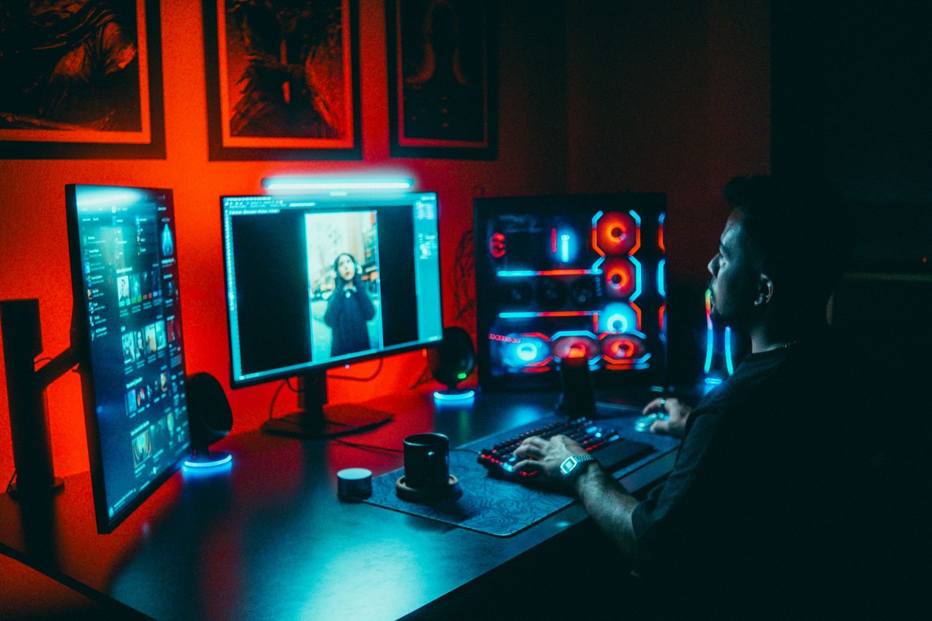 A developer working on a multi-screen setup in a dark, neon-lit room.